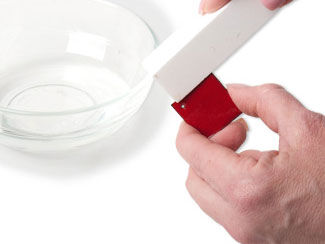 Enameled metal being cleaned with allundum stone